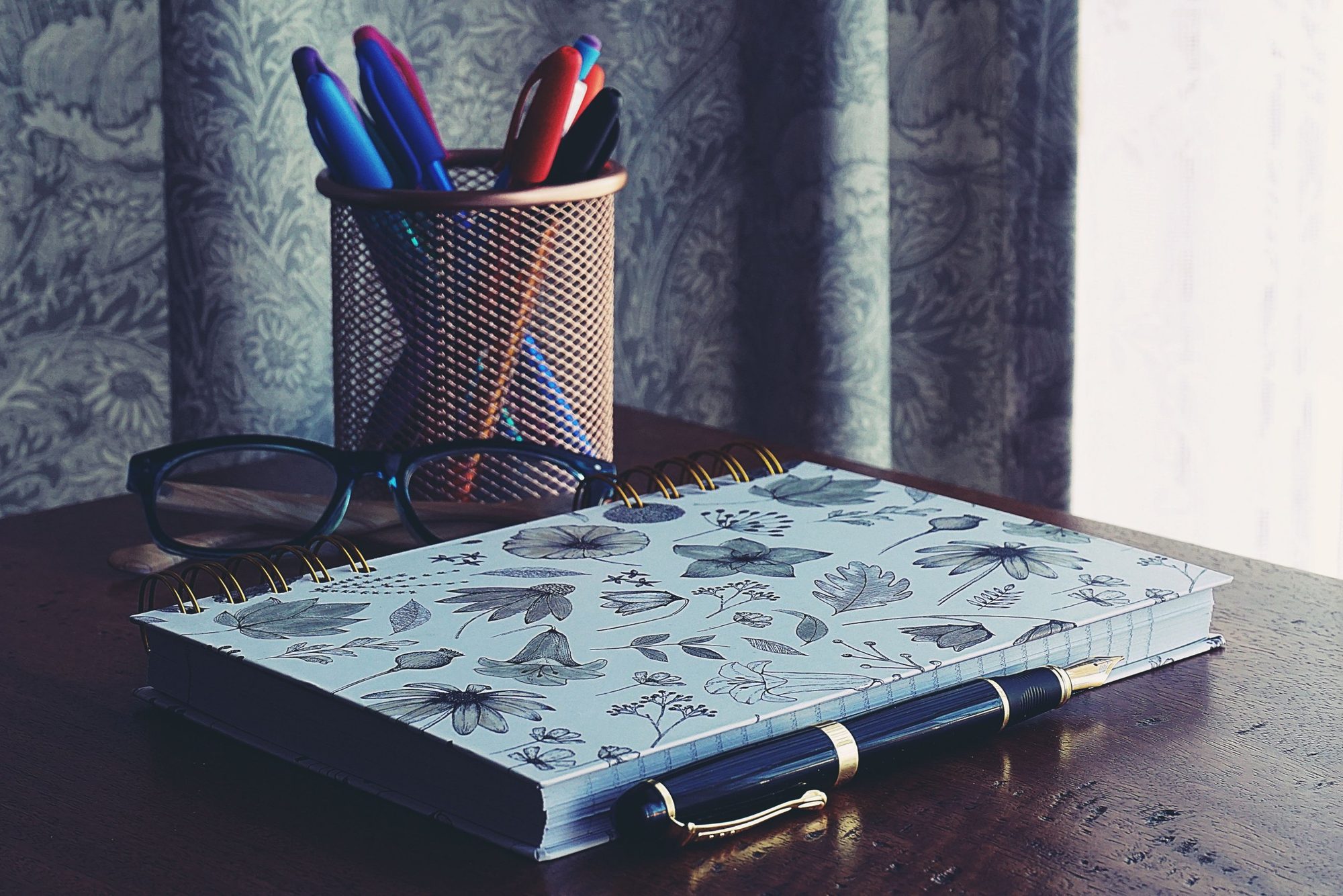 Carnet, stylos et lunettes sur un bureau